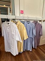 Five assorted color short-sleeve button-up shirts on hangers