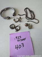 Entire assortment laid out showing cuff bracelet, chain, three earring pairs and single drop, with .925 note for scale