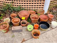 All assorted terracotta, ceramic, metal and wood planters arranged on ground