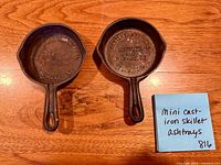 Top view of both cast iron mini skillet ashtrays showing advertising text and overall condition