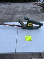 Full view of hedge trimmer showing housing, handle, cord exit and rusty blade