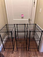 Three black metal wire shelving units