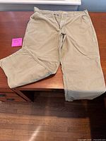 Front view of khaki Carhartt carpenter pants displayed on table