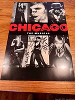 Front view of the signed Chicago: The Musical poster showing images, red title, and multiple signatures