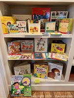 Single photo showing three shelves filled with children’s board books and hardcover picture books placed upright and stacked