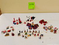Tabletop view of all assorted wooden Christmas ornaments, figures, plaid bow, and apple cluster