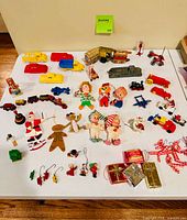 Full view of assorted vintage Christmas ornaments and small toys laid out on white table