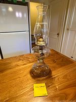Full view of clear glass and brass oil lamp on table
