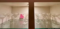 Front view of all 12 clear glass champagne coupe glasses on shelf