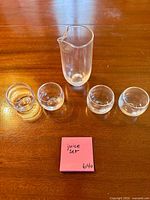 clear glass pitcher and four matching tumblers displayed on wooden surface
