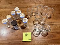 All glass spice jars grouped by size and lid presence on wooden surface