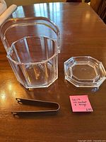 Clear octagonal acrylic ice bucket with handle, separate lid, and metal tongs displayed on table
