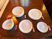 Stacks of white Corelle plates and bowls grouped by type on table