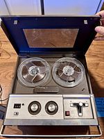 Recorder opened showing tape heads and two clear reels