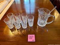 Pitcher, seven tumblers and stirrer arranged on table