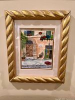 Front view of framed watercolor street scene in gold rope frame