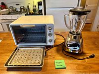 GE toaster oven with tray and rack beside Oster blender with jar and lid on countertop