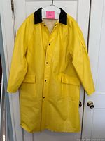 Front view of knee-length yellow raincoat with black collar and pockets
