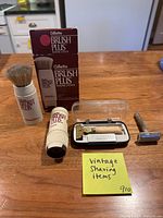 Group shot of all items including Gillette Brush Plus brush, refill, box, Eversharp razor in case, and chrome safety razor