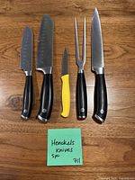 All five utensils laid out on wood surface showing blades and handles
