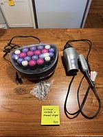 Hot rollers set with rollers in base, clear clips, and travel hair dryer laid out on table