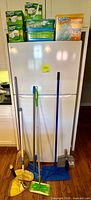 Group shot showing five Swiffer refill boxes on refrigerator and five cleaning tools leaning in front