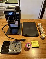 Front view of Keurig coffee maker with drip tray removed, power cord, reusable pod, six K-Cup pods