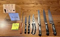 Full view of five knives, shears, honing rod, and wooden block on table