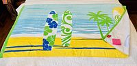 Full view of towel showing surfboard beach scene design and attached tags