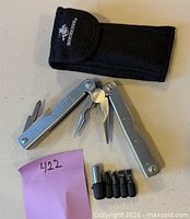 Multi-tool opened with pliers, sheath, bit adapter and four bits visible