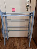 Full view of light blue distressed wooden quilt rack against a door