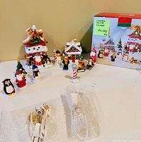 Overall view of ceramic lighted houses, figurines, light cords, and original box