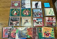 All 20 jewel-case Christmas audio CDs laid out on table