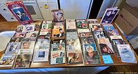 Overhead view of approximately 45 music CDs and two longbox sets laid out on table showing titles and condition