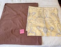 Brown and yellow tablecloths laid flat on bed