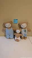 Front view of three tan plush bears in outfits