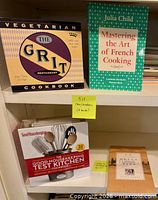 Shelf view showing the four cookbooks: The Grit Vegetarian, Julia Child Mastering the Art of French Cooking, Good Housekeeping Test Kitchen boxed cookbook, La Table cookbook