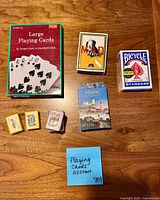 All eight playing card decks on table showing packaging fronts and relative sizes