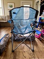 Light-blue mesh folding camp chair front view, bag behind