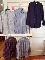 Five Orvis long-sleeve button-down shirts hung on a door showing front view and patterns