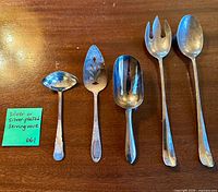 Front view of all five silver-plated serving pieces laid out on table