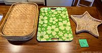 Stack of five rectangular wicker trays, one green floral melamine tray, one star wicker tray on table