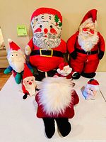 Group photo showing all eight plush Santa decorations on tabletop