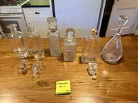 Front view showing all seven decanters and loose stoppers on tabletop