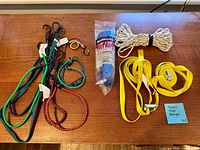 All items laid out: bungee cords, packaged blue rope, coiled white rope, yellow straps
