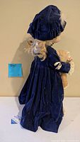Side view of larger doll in navy velvet holding smaller peach-dressed doll