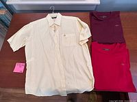 All three shirts laid out: yellow gingham button-down, burgundy tee, red tee