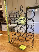Full view of black metal wine rack with tape measure indicating height