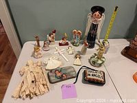 Overall view of assorted angel figurines, crosses, cloth topper and pouches on table