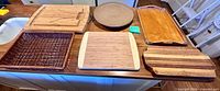 All six cutting boards, serving trays and wicker basket on countertop